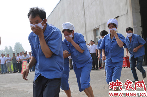 纺纱工人用湿毛巾捂住口鼻分别从各个岗位上迅速逃离火灾区