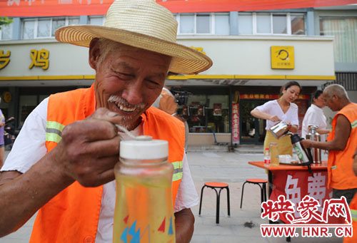 7月28日，环卫工人在平顶山市宝丰县百岁鸡百岁鸭免费茶水点接绿豆茶解酷暑。