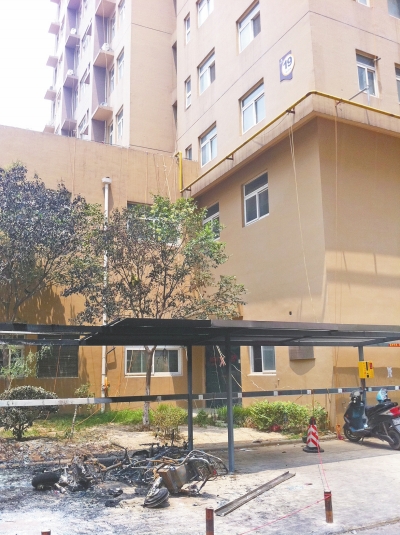 在园田花园小区着火的车棚前，给电动自行车充电私扯的电线就像蜘蛛网一样。