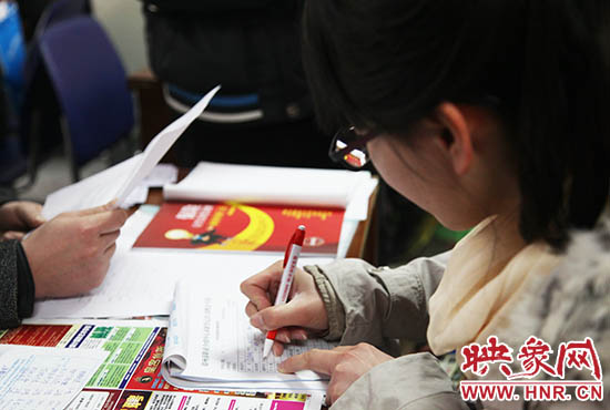 图为招聘会现场一名求职者填写材料