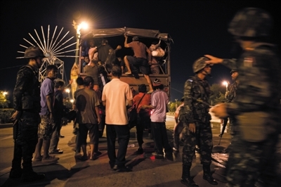 22日晚,“红衫军”示威者收拾好行李坐上军方提供的卡车离开集会地点。