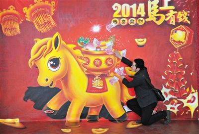 1月25日，南京市，一名男子与“马上有钱”的3D画互动留影。
