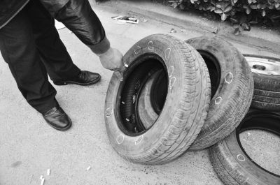 杨先生把轮胎上的针眼用粉笔圈出