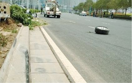 脱离车身的右前轮倒在路上。