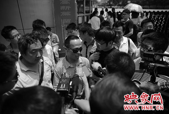 李金生在考点门口接受众多媒体记者采访。